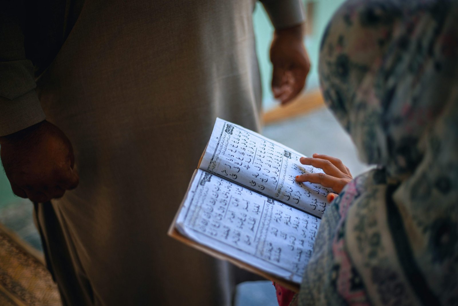 A young girl studies Arabic text in Keran, focusing intently on the book.