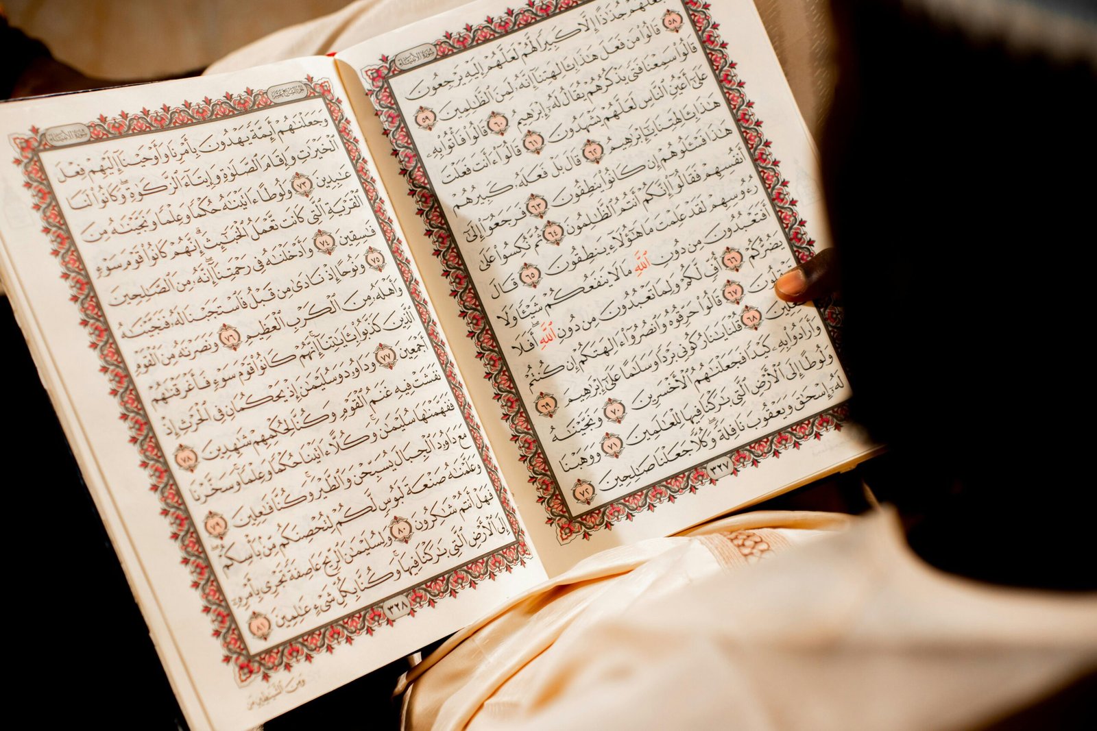 A person reading an open Quran, focusing on religious text and spiritual reflection.